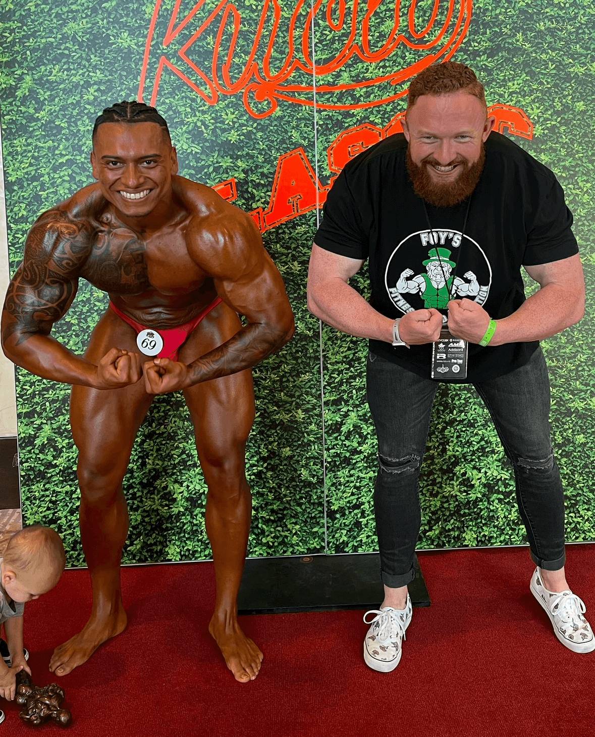 Personal Trainer Marlin Foy flexes with a client at a bodybuilding competition